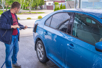 Man washing his car in a self-service car wash station.A man washes a car on his own. Car wash...