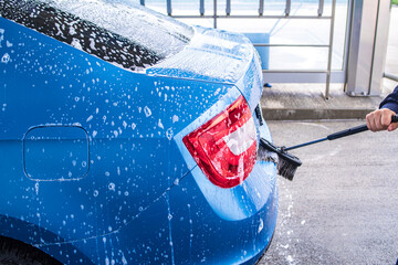 Man washing his car in a self-service car wash station.A man washes a car on his own. Car wash...