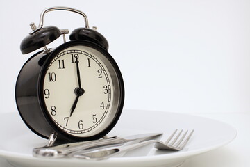Alarm clock with fork and knife on the plate. Time to eat. Weight loss or diet concept. An image of...