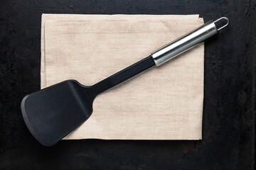top view on spatula placed on folded towel lying on old rustic background