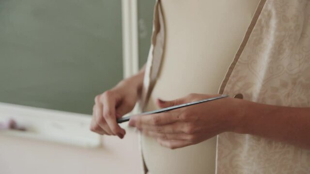 pregnant woman teacher with a big belly and a pointer leads a lesson at school