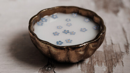 Milk and blue flowers in a bronze bowl.