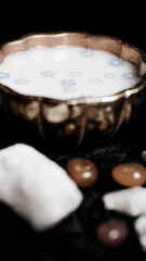 Milk and blue flowers in a bronze bowl.