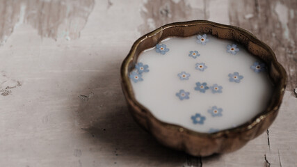 Fototapeta na wymiar Milk and blue flowers in a bronze bowl.