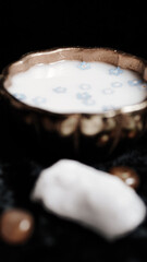 Milk and blue flowers in a bronze bowl.