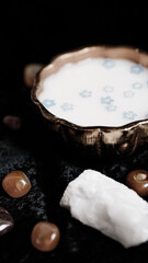 Milk and blue flowers in a bronze bowl on a dark background. 