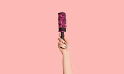 Cropped view of girl holding hair brush on pink background, close up