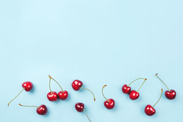 Bright pattern of ripe cherries on a blue background. Flat lay, top view. Copy space for your text.