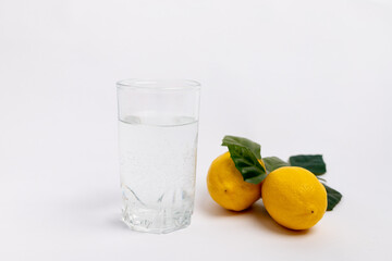 water in a glass with lemons on a white background, lemon water, a glass of water in the morning, healthy lifestyle, place for text