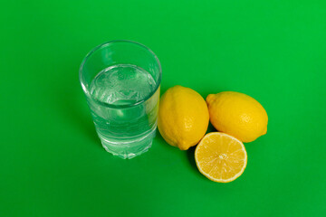 water in a glass with lemons on a green background, lemon water, a glass of water in the morning, healthy lifestyle, place for text