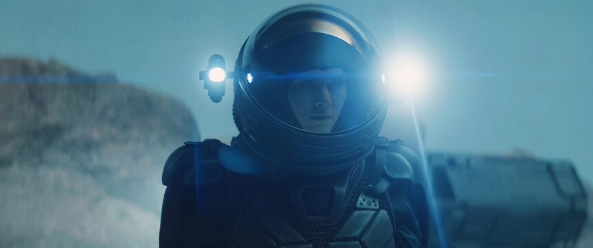 Caucasian female astronaunt wearing a space suit exploring planet surface, night shot