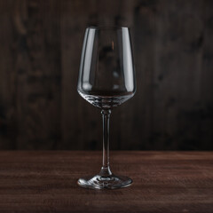 Empty wine glass on wooden table against dark background in bar. Catering Concept