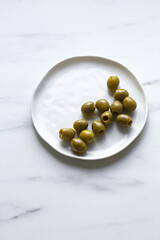 green olives on white marble background with copy space