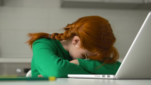 Red-haired kid napping in front of laptop, tired of extra classes and tutoring