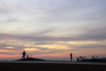 Silhouette of a cyclist on the beach at sunrise.