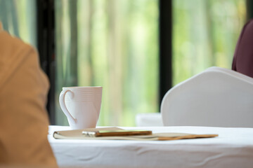 close up to seminar audience with their glass and gadget on the table.