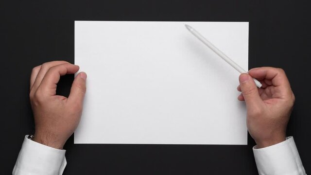 top view of a blank sheet of paper and a businessman's hands on a black table, white shirt and wrist watch