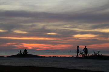 Silhouette of a cyclist on the beach at sunrise.