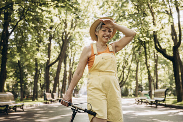An elderly woman is riding a scooter in the park