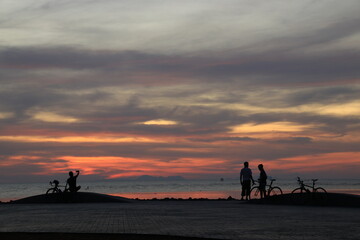 Silhouette of a cyclist on the beach at sunrise.