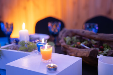 romantic candles are decorated on the dinner table with square white wood box and little tree on it.