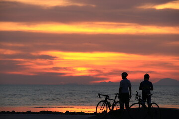 Fototapeta na wymiar Silhouette of a cyclist on the beach at sunrise.