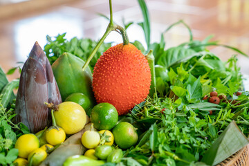 Various local Thai herbs in the basket such as Gac fruit, lime, basil, etc. all of this is an ingredient for healthy cooked food.