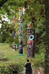 Aboriginal / Native American tall wooden totem poles, aligned in a row, all with stacked animal...
