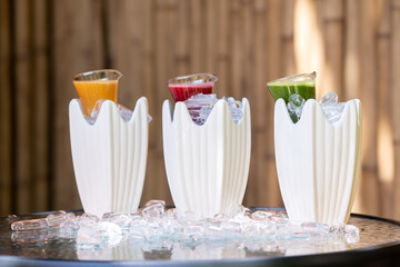 Multiple and mixed herb with fruit juice to red green and orange colour drink in little glass jar that was decorated with ice around.