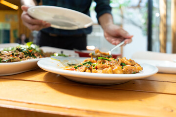 Fried Stir Sweet and sour sauce with Vegetable and Pork with blue man hand is scooped with his spoon.
