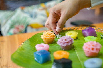 Thai Chef's hand is decorating Varieties traditional colorful Thai desserts set; steaming flour, black custard, coconut custard & steaming bean, layer pudding cake