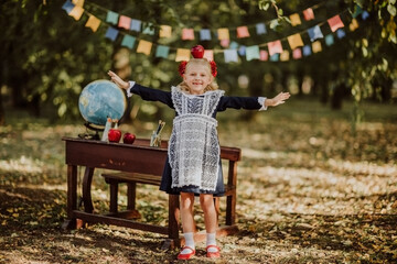 Young girl in school uniform playing with red newton apple. Flags background