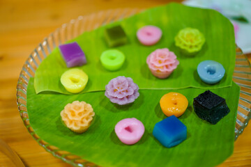 Varieties traditional colorful Thai desserts set; NamDokMai (steaming flour), PiekPoon (black custard), LeumKluen (coconut custard & steaming bean), KanomChan (layer pudding cake)