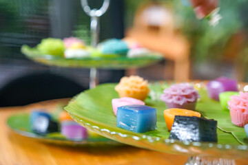 Varieties traditional colorful Thai desserts set; NamDokMai (steaming flour), PiekPoon (black custard), LeumKluen (coconut custard & steaming bean), KanomChan (layer pudding cake)