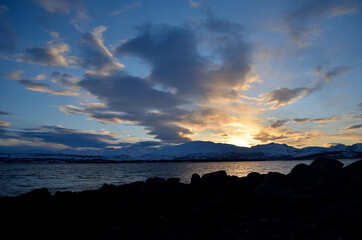 golden vibrant sunset over snowy mountain and fjord landscape