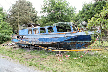 Old devastated boat under construction on river bank