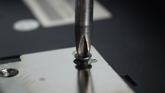 screwdriver unscrews a screw, closeup