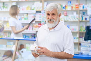 Obraz premium Senior man choosing medicine at pharmacy.