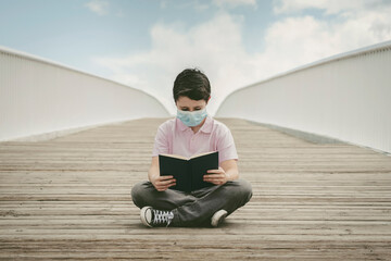 kid wearing medical mask sitting reading a book