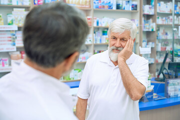 Senior customer with toothache in drugstore.