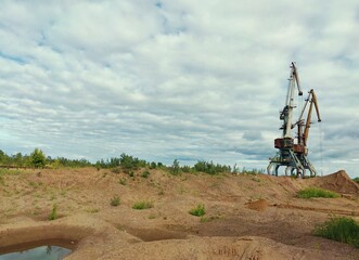 two huge cranes on a sand quarry against a blue cloudy sky