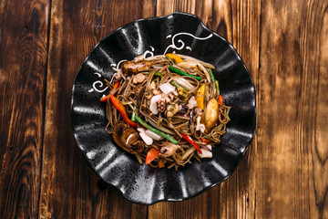 Seafood soba noodles wok in a black plate