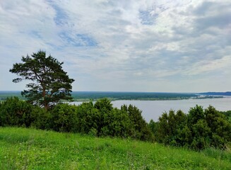 blue cloudy sky above the river and trees on top of the mountain