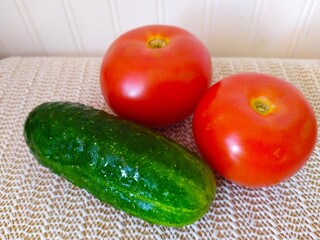 still life two red ripe tomatoes and one green cucumber on a white background
