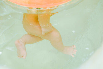 Fototapeta premium Newborn baby swimming in the swimming pool with the swim ring on neck