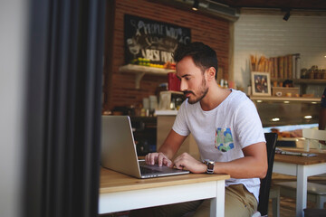  handsome man reading text message during work on net-book in comfortable coffee shop