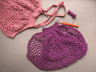 String bag in the process of knitting. Lilac mesh bag, crochet hook and crochet the remaining yarn. The concept of creating a product.