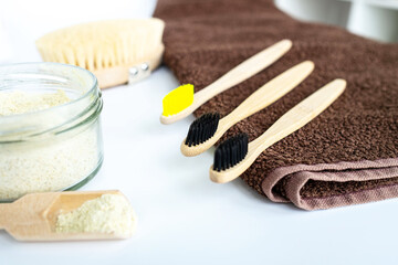 Eco natural bamboo toothbrush on white background with toiletries, natural soap, scrub, body brush and soft broun towel. Zero waste concept. Choice plastic free items. Selective focus