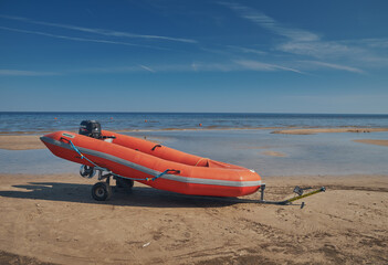 Red rescue boat on the sandy shore of the Baltic Sea.