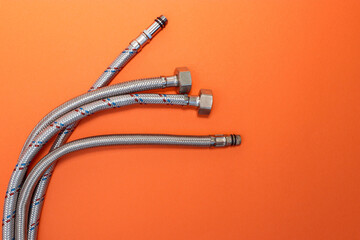 Flexible water hoses in a metal spout for connecting plumbing equipment. Bright orange gradient...